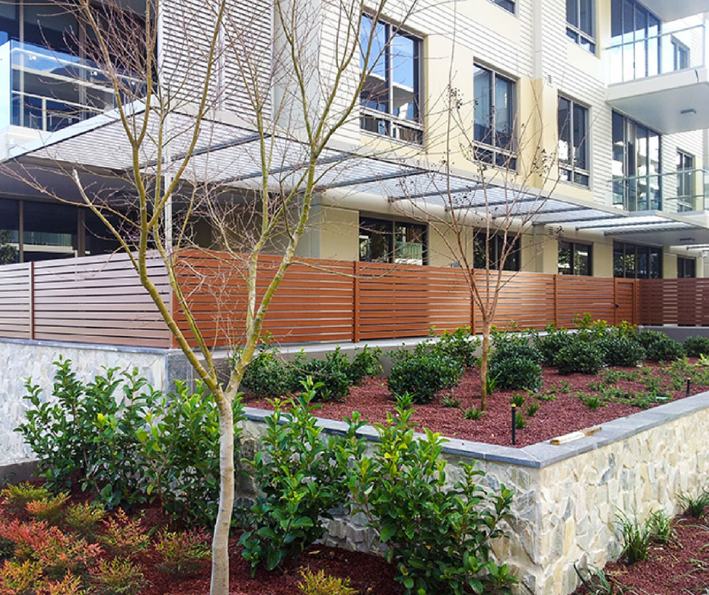 Aluminijumske ograde cena sa drvo dekor letvicama ispred poslovnog objekta sa zelenilom — Savalux